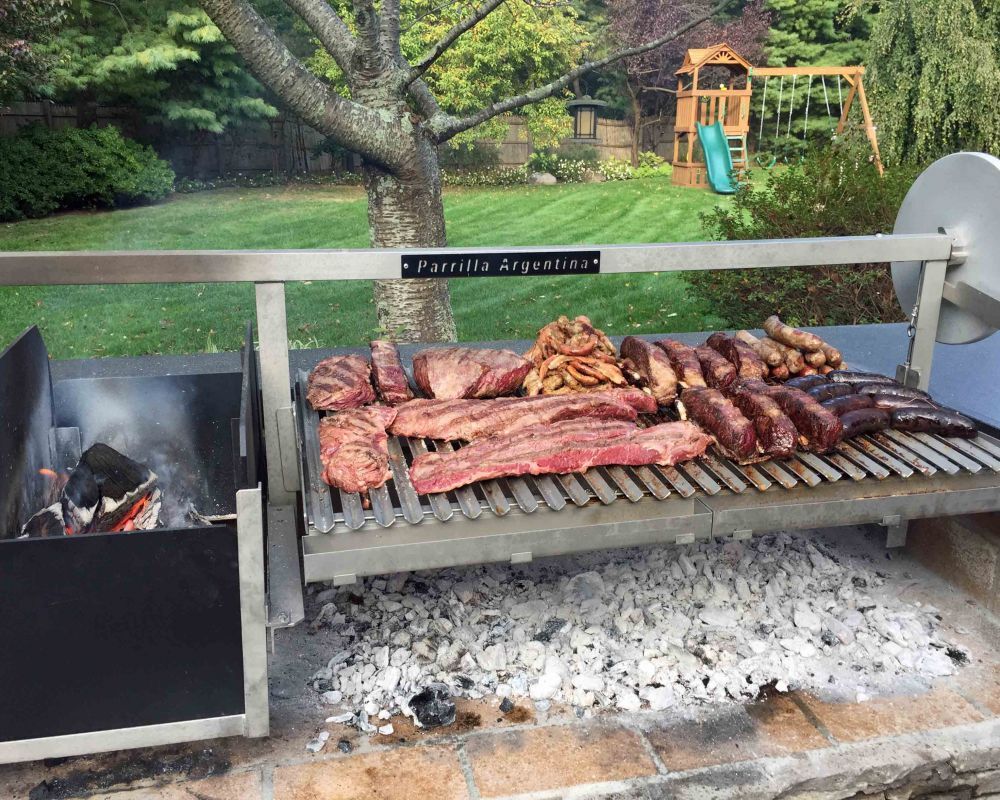 Professional Argentine parrilla grill with meat cooking over wood embers