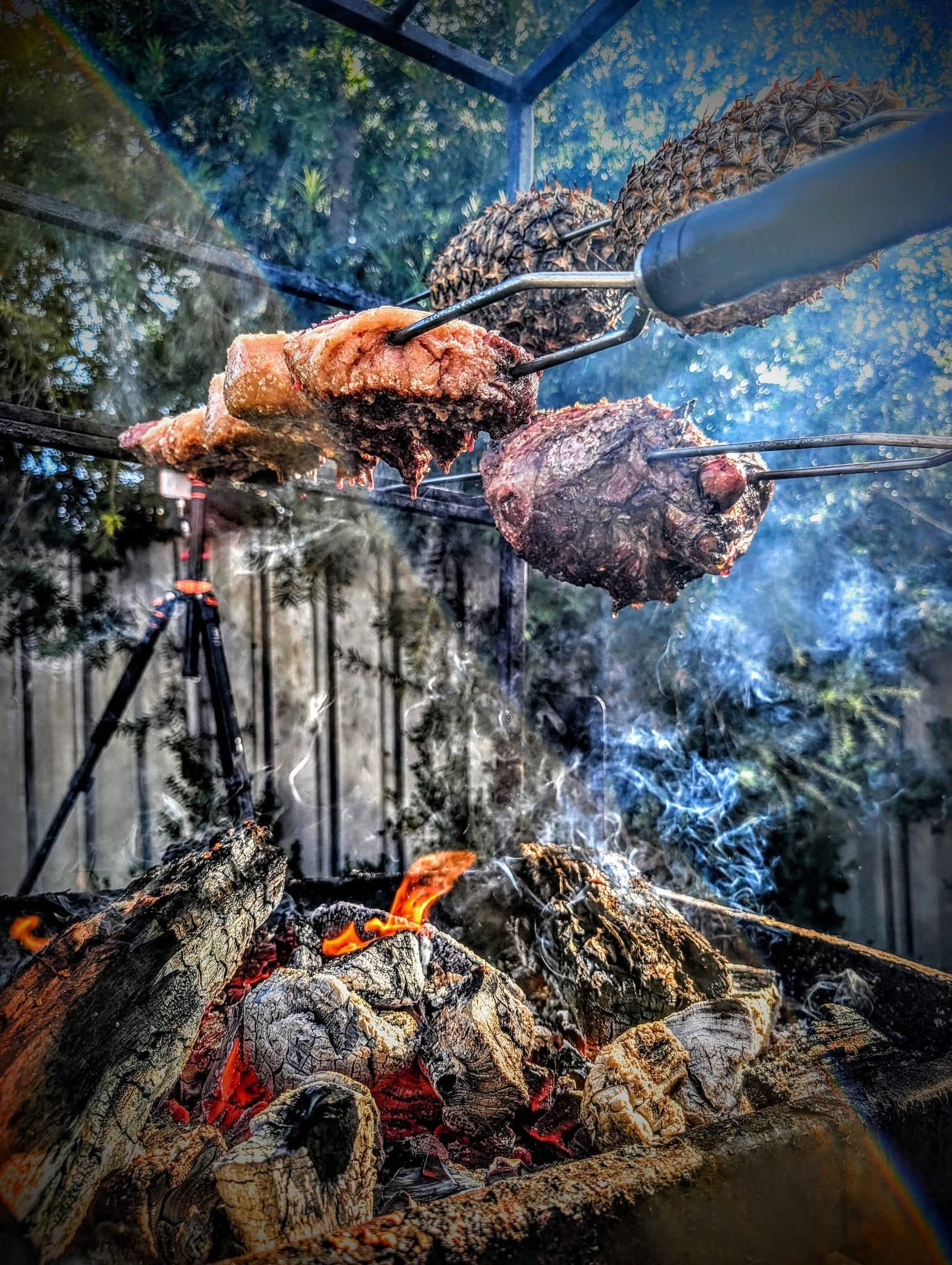 Meat and pineapple on skewers over open fire